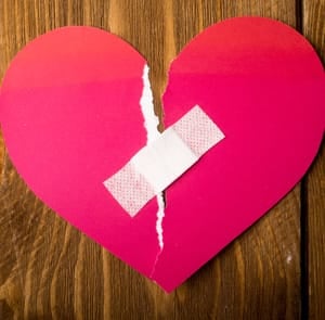 Photo of a ripped paper heart with a Band-Aid over it Photo of a ripped paper heart with a Band-Aid over it