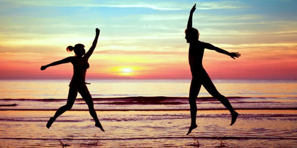 A photo of a couple jumping on the beach A photo of a couple jumping on the beach