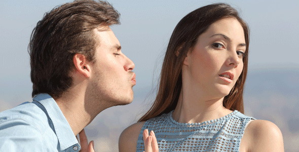 Photo of a man offering a woman an unwanted kiss