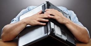Photo of a guy burying his head under a laptop