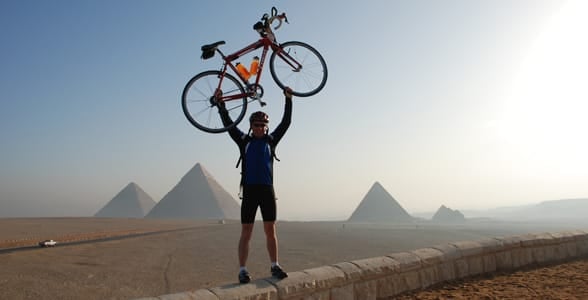 Photo of a man posing with his bicycle above his head