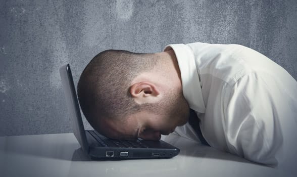 Photo of a man with his head on a laptop