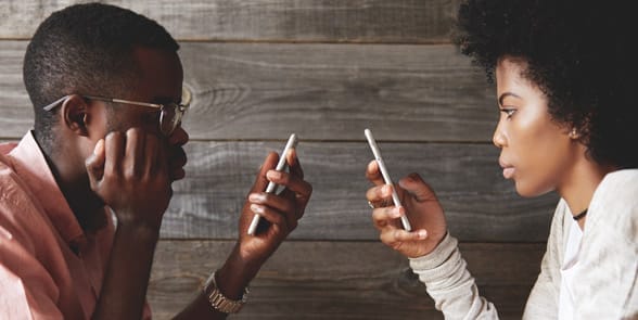 Photo of a couple on their phones and ignoring each other