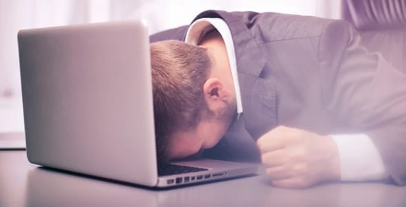 Photo of a guy with his head on his laptop