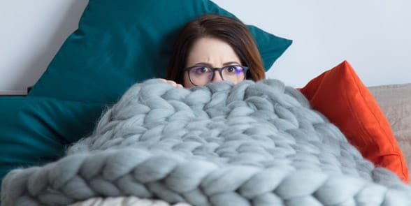Photo of a woman hiding under blankets