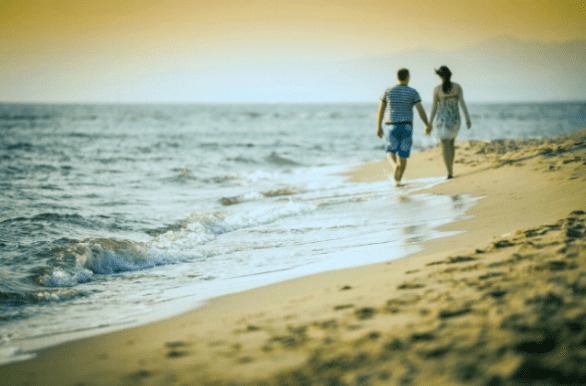 Photo of couple walking on the beach Photo of couple walking on the beach