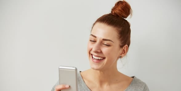 Photo of a woman holding a cellphone and laughing