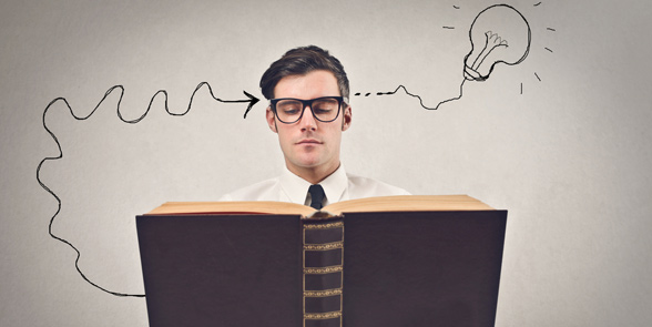 Photo of a man reading a book with a light bulb above his head