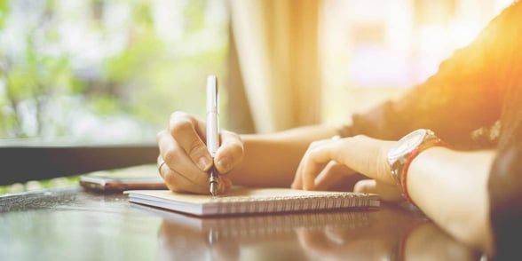 Photo of man writing in notebook