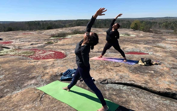 Photo of two people practicing yoga on Arabia Mountain