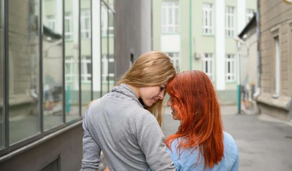 Photo of two women leaning toward each other