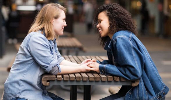 Photo of two women leaning toward each other