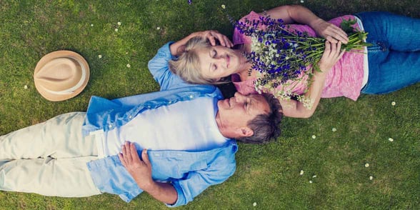 Photo of mature couple laying in the grass