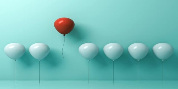 Photo of red balloon in group of white balloons
