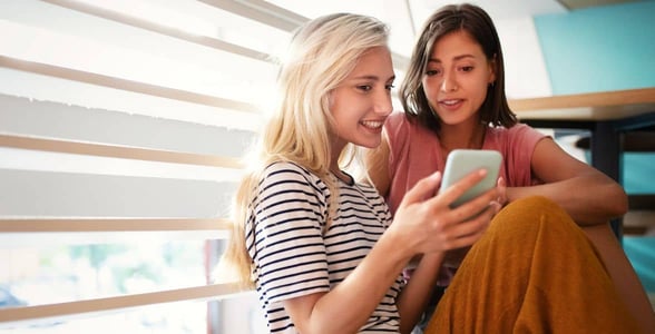 Photo of two women with a phone Photo of two women with a phone