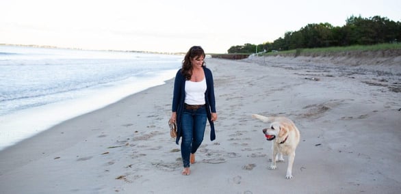 Photo of Noreen Rochester walking on the beach with her dog