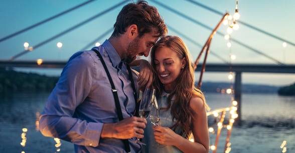 Photo of a couple drinking champagne near water