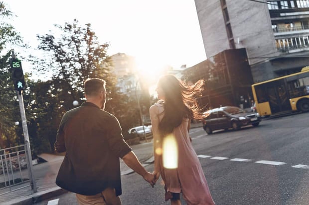 Following dreams together. Rear view of beautiful young couple holding hands while walking through the city street