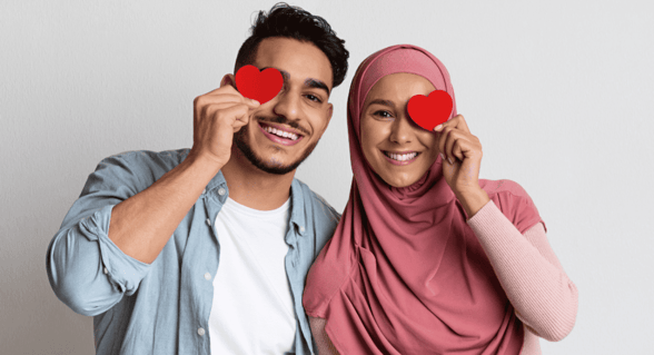 couple holding heart cut-outs over their eyes