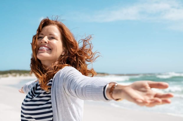 Happy mature woman with arms outstretched feeling the breeze at beach. Beautiful middle aged woman with arms up dancing on beach. Mid lady feeling good and enjoying freedom at sea, copy space. Happy mature woman with arms outstretched feeling the breeze at beach. Beautiful middle aged woman with arms up dancing on beach. Mid lady feeling good and enjoying freedom at sea, copy space.