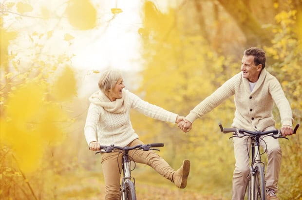 Active seniors riding bike in autumn nature. They relax outdoor.