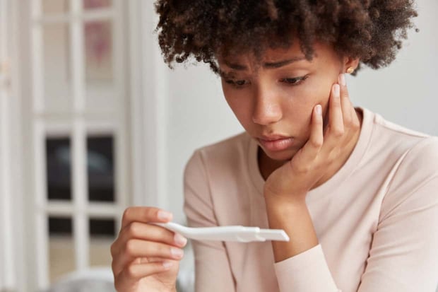 Displeased frustrated African American woman looks stressfully at pregnancy test, finds out she will become mother, looks desperately at result. Close up shot of young lady has problems with fertility Displeased frustrated African American woman looks stressfully at pregnancy test, finds out she will become mother, looks desperately at result. Close up shot of young lady has problems with fertility