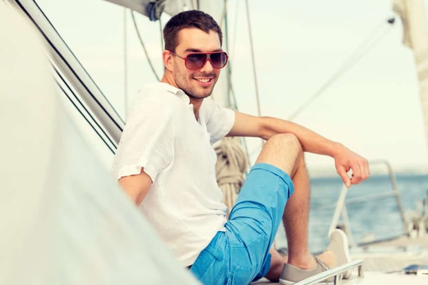 vacation, holidays, travel, sea and people concept - man in sunglasses sitting on yacht deck