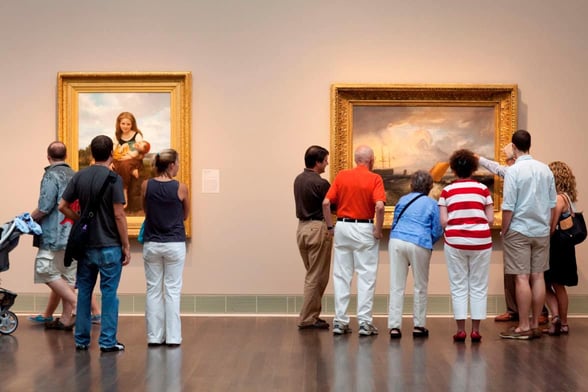 People look at large paintings in museum People look at large paintings in museum