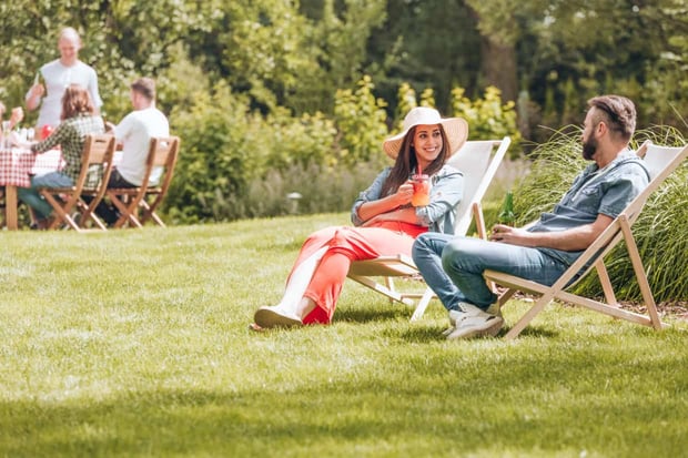 woman and man sitting on deckchairs and flirting during afternoon yard party.