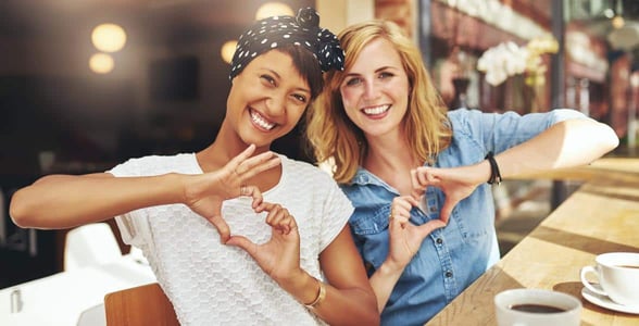 Photo of two women making hearts with their hands Photo of two women making hearts with their hands