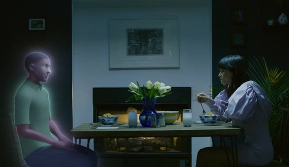 woman and AI avatar sit across from each other at table
