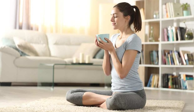 Photo of woman doing yoga and holding a tea cup