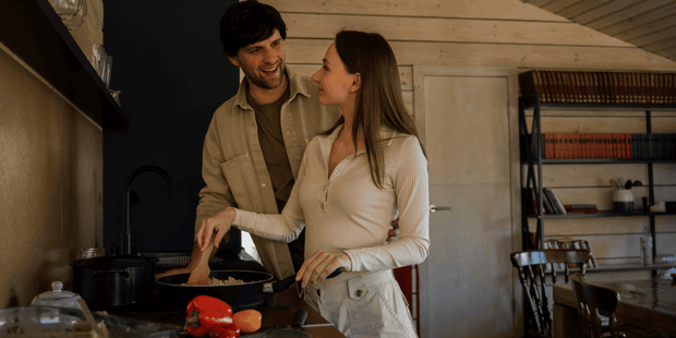 Woman and man cooking and smiling at each other