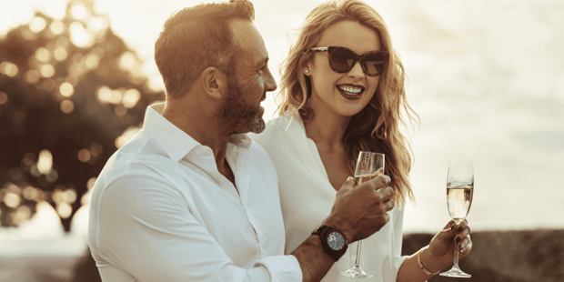 Woman and man wearing white holding champagne glasses