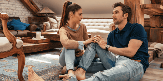 Woman and man sitting on floor having a serious conversation.