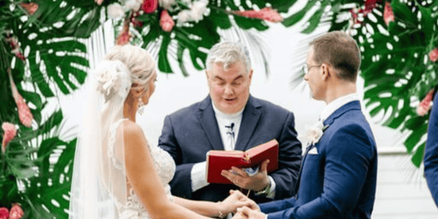 Couple saying their vows and holding hands in a tropical setting