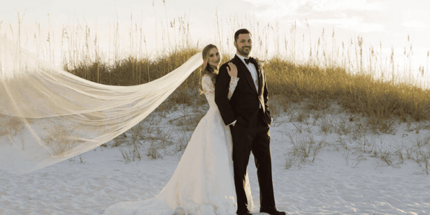 Bride and groom on beach with veil flowing in the wind Bride and groom on beach with veil flowing in the wind