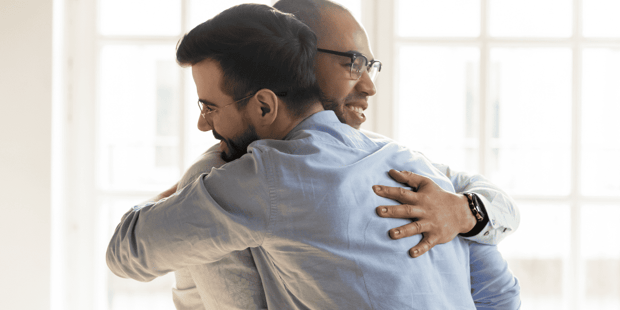 Two men professionally dressed and hugging