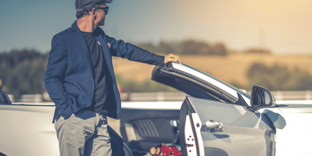 Older, successful man holding expensive car door open with roses inside