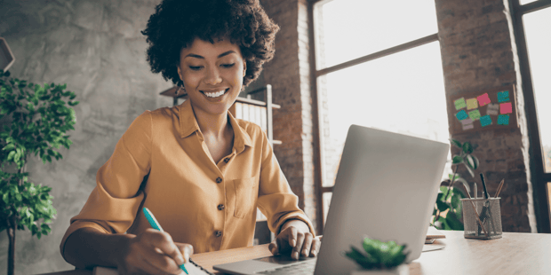 Black woman smiling and writing on notepad Black woman smiling and writing on notepad