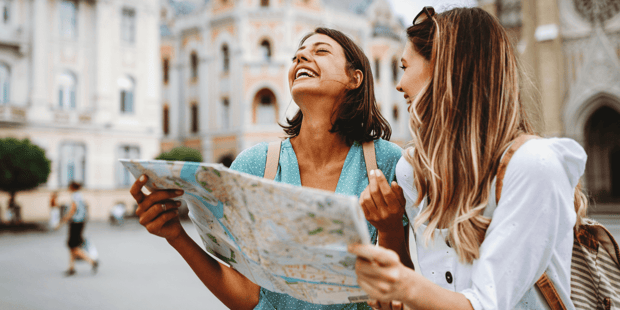 Two young women looking at map while traveling