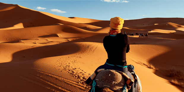 Woman riding camel in desert wearing cultural garb