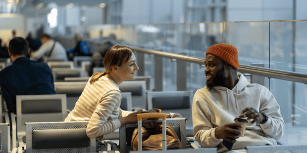 White woman and Black man making conversation while waiting in an airport terminal
