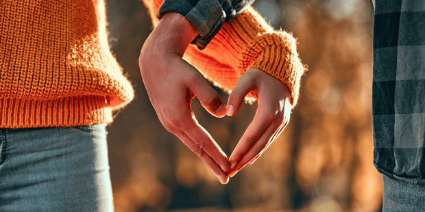 Young man and woman holding hands together forming a heart