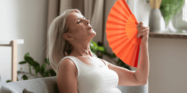 Older woman fanning herself during hot flash Older woman fanning herself during hot flash