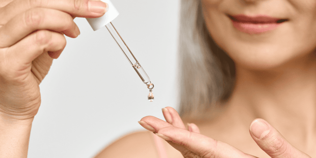 Senior woman using dropper of hyaluronic acid