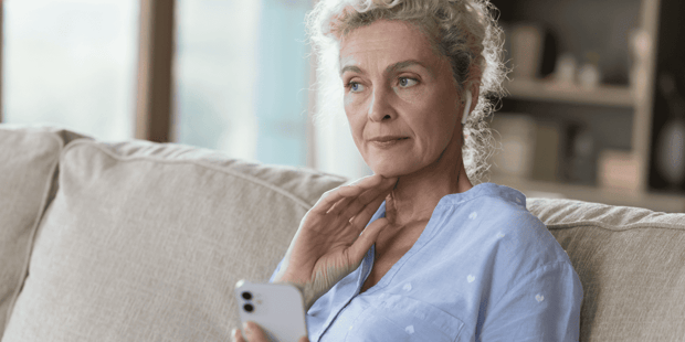 Older woman holding cellphone and looking concerned