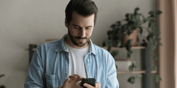 Man with facial hair looking down at cellphone