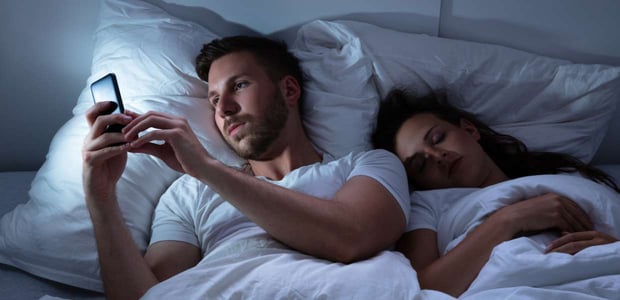 Photo of a husband texting in bed Photo of a husband texting in bed