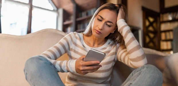 Photo of a woman frowning at her phone